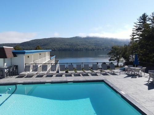 a swimming pool with chairs and a view of a lake at Lakefront Terrace Resort in Lake George
