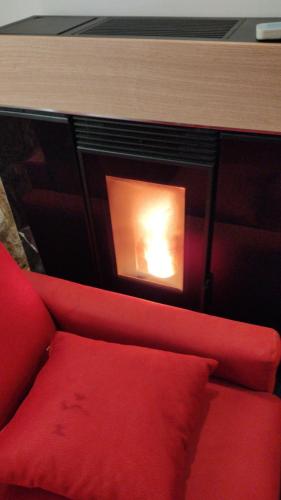 a red couch in front of a fireplace at La Casa del Poeta , un romantico chalet da mille e una notte in Petralia Soprana