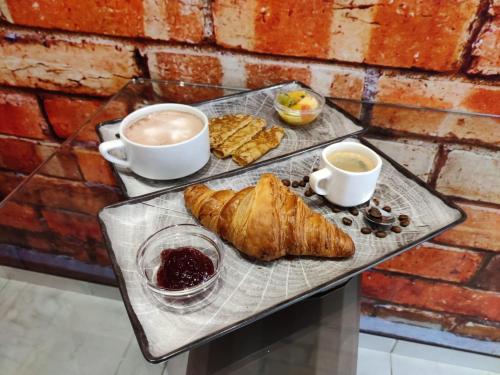 a tray with croissants and two cups of coffee at The Originals Boutique, Hôtel de l'Univers, Montluçon in Montluçon