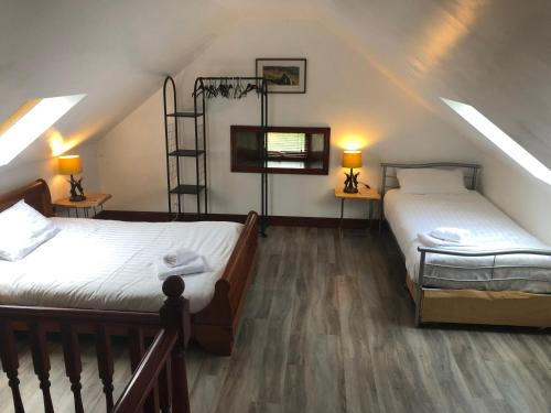 two beds in a attic room with two lamps at Merrick Cottage in Bargrennan