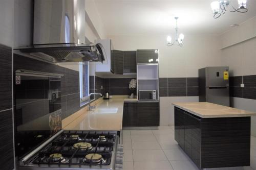 a kitchen with black cabinets and a stove top oven at THE POOL LABONE in Accra