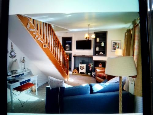 a living room with a blue couch and a staircase at The Wee Anchor in Arbroath
