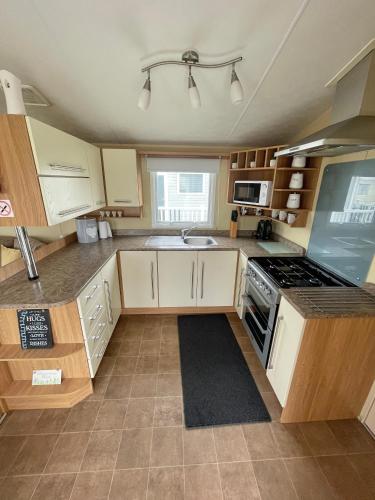 a kitchen with white cabinets and a stove top oven at Golden Palm Chapel St Leonards 8 Berth 3 Bedroom Caravan in Skegness