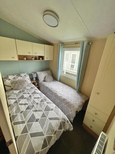 a small bedroom with a bed and a window at Golden Palm Chapel St Leonards 8 Berth 3 Bedroom Caravan in Skegness