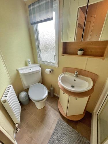 a small bathroom with a toilet and a sink at Golden Palm Chapel St Leonards 8 Berth 3 Bedroom Caravan in Skegness