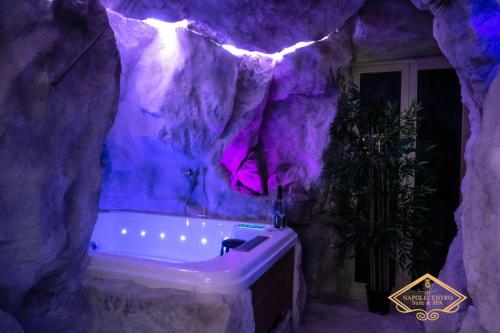 a purple bathroom with a tub in a rock wall at Napoli Centro Suite e Spa in Naples