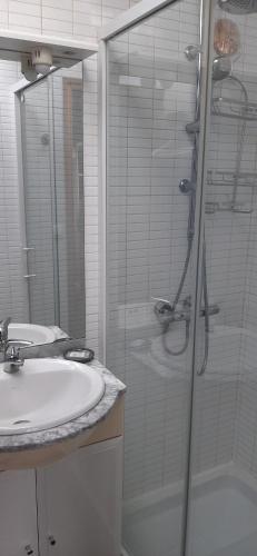ein Bad mit einer Glasdusche und einem Waschbecken in der Unterkunft Aux 77 Nuitées in Trilport