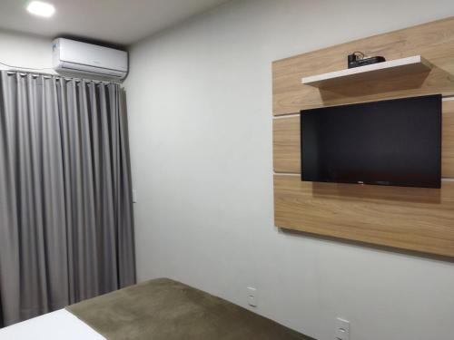 a bedroom with a flat screen tv on a wall at Chapada Confort Flats in Alto Paraíso de Goiás