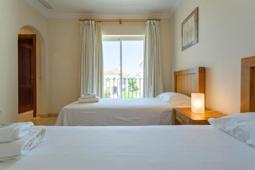 a hotel room with two beds and a window at Arcos Gardens Sol Rent Golf in Arcos de la Frontera