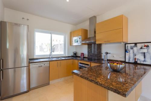 a kitchen with wooden cabinets and a granite counter top at Arcos Gardens Sol Rent Golf in Arcos de la Frontera