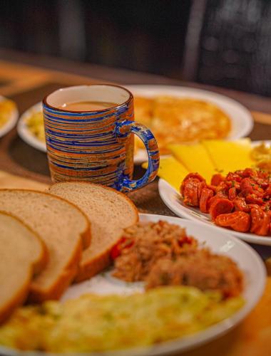 a table with plates of food and a cup of coffee at Metro Hotel Couva in Couva