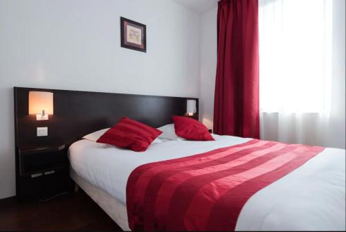 a bedroom with a large bed with red pillows at Appart'City Classic Lyon Part-Dieu in Lyon