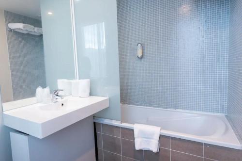 La salle de bains est pourvue d'un lavabo, d'une baignoire et d'un miroir. dans l'établissement Appart'City Classic Lyon Part-Dieu, à Lyon