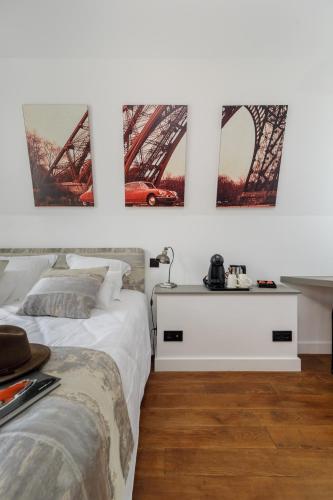 two beds in a room with three pictures on the wall at L'Hôtel Particulier - Paris Asnières in Asnières-sur-Seine