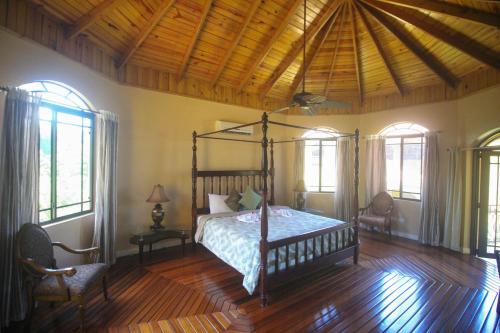ein Schlafzimmer mit einem Himmelbett in einem Zimmer mit Fenstern in der Unterkunft Luxury 10 Bedroom Villa-Millbrooks in Montego Bay