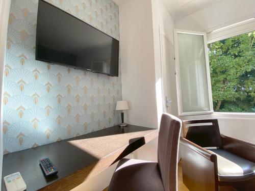 a room with a desk and a television on a wall at La Villa Paris - B&B in Paris