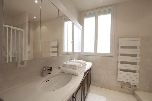 a white bathroom with a sink and a mirror at La Villa Paris - B&B in Paris
