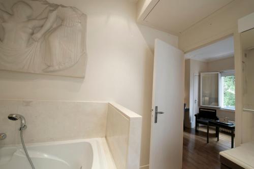 a bathroom with a bath tub with a painting on the wall at La Villa Paris - B&B in Paris