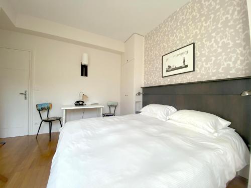 a bedroom with a large white bed and a desk at La Villa Paris - B&B in Paris