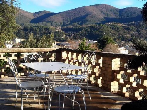 a table and chairs on a patio with mountains in the background at Les Horizons - SPA-JACUZZI - MASSAGE- SAUNA - 4 SAISONS - Piscine chauffée Toute l'année - 800m centre ville Nyons in Nyons