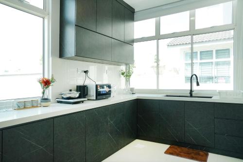 a kitchen with black cabinets and a sink at Desaru KTV Classical Elegant Style by Joyfully 2M2 in Desaru