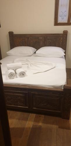a bed with white sheets and pillows on it at Silver Hill Guesthouse in Gjirokastër