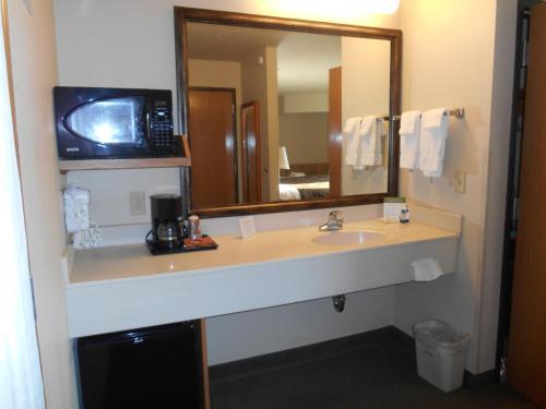 a bathroom with a sink and a microwave at AmericInn by Wyndham Wetmore Munising in Wetmore