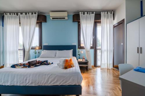 a bedroom with a bed with blue walls and windows at AppartaHotel in Beinasco