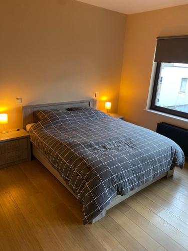 uma cama num quarto com dois candeeiros e uma janela em 't Genot em Blankenberge