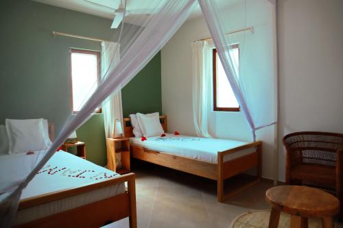 two beds in a room with two windows at Kijani Beach Villas in Bwejuu