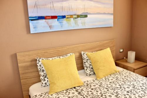 Un dormitorio con una cama con almohadas amarillas y una pintura en Beautiful Ocean View Apartment, en Porís de Abona