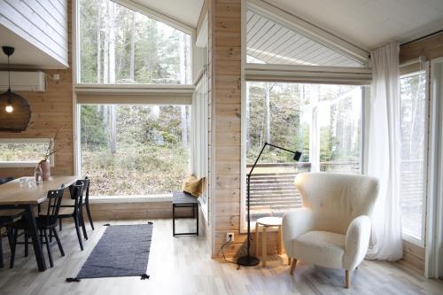 a living room with a table and chairs and windows at Villa Laidike with sauna/fireplace, 80 km Helsinki in Suomusjärvi