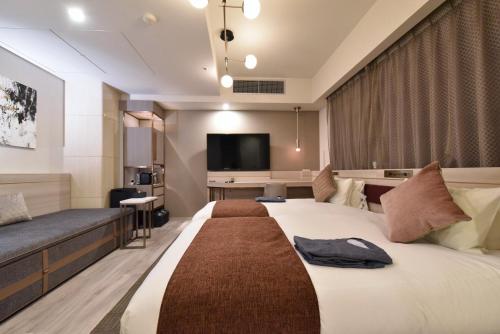 a hotel room with a large bed and a flat screen tv at Hotel Cordia Osaka Hommachi in Osaka