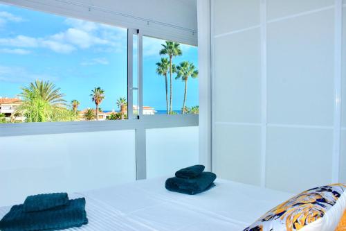 a bedroom with a bed with a window with palm trees at VILA CARLA - 3BDR + 3BATH in Amarilla Golf in San Miguel de Abona