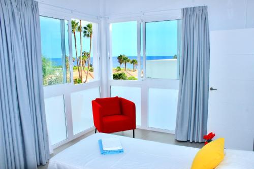 a bedroom with a red chair and large windows at VILA CARLA - 3BDR + 3BATH in Amarilla Golf in San Miguel de Abona