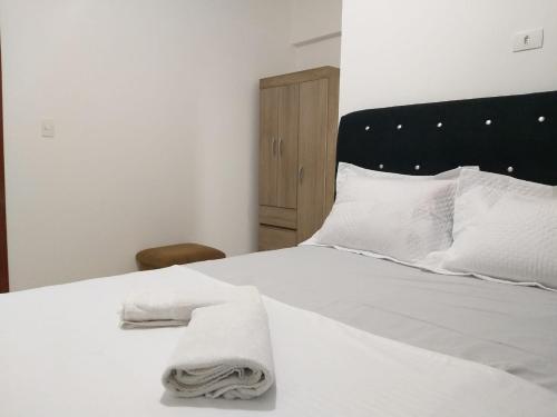 a white bed with white pillows and towels on it at Apartamento Hospedagem Cidade Verde 2 MT in Maringá