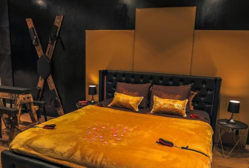 a bedroom with a large bed with a yellow blanket at La loveroom bdsm grassoise "La chambre des désirs" in Grasse
