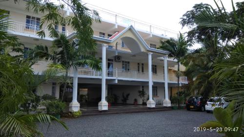 a large white building with palm trees in front of it at Alpha Villa in Flic-en-Flac