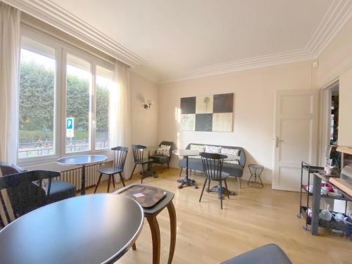 - une salle d'attente avec des tables, des chaises et des fenêtres dans l'établissement La Villa Paris - B&B, à Paris