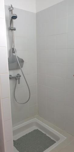 une salle de bain blanche avec une douche avec un tuyau dans l'établissement Studio Nikita Manganao, Appartement Standing Vue mer, à Saint-François