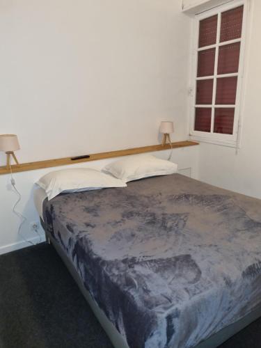 a bed in a bedroom with two pillows and a window at Hotel Café de la Gare in Sainte-Foy-la-Grande
