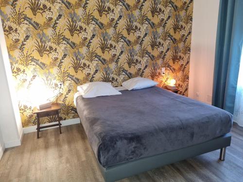 um quarto com uma cama com papel de parede azul e dourado em Hotel Café de la Gare em Sainte-Foy-la-Grande