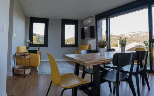 O Feixoal في Hio: غرفة طعام مع طاولة خشبية وكراسي صفراء