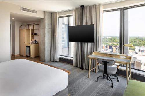 a hotel room with a bed and a desk and windows at Jasper Hotel in Fargo