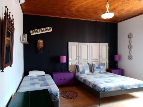 dwa łóżka w pokoju z czarnymi ścianami i purpleitures w obiekcie Pátio das Andorinhas w mieście Ferreira do Alentejo