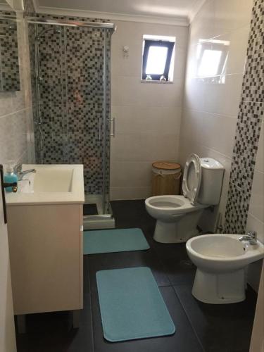 a bathroom with two toilets and a sink and a shower at Casa das Bonecas in Mangualde