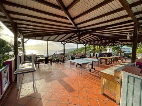 a patio with tables and chairs and a wooden roof at Le Nid Tropical in Bouillante