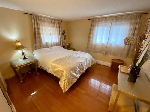 a bedroom with a white bed and a wooden floor at The Country Barn in Port Alberni