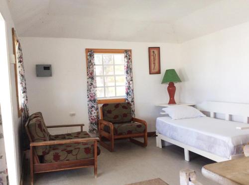 a bedroom with a bed and a chair and a window at Rest Haven Beach Cottages in Saint Joseph