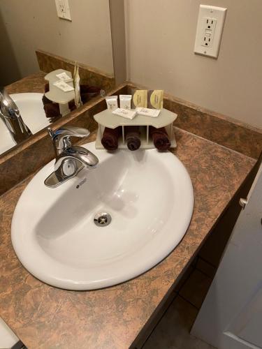 a bathroom counter with a sink and a mirror at Aspen Motor Inn in Drayton Valley